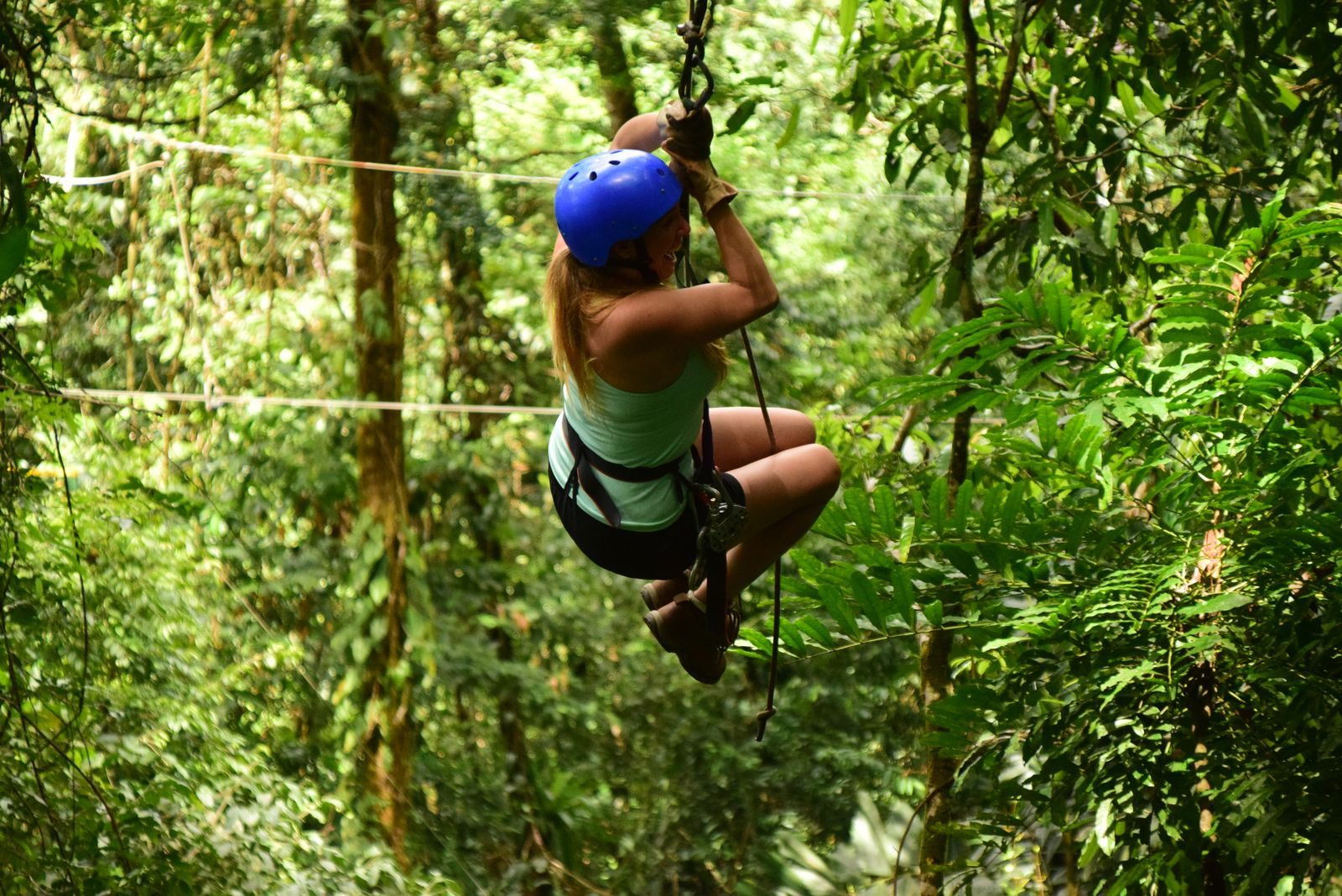 A woman in a helmet ziplining through lush Costa Rican rainforest on an adventure excursion