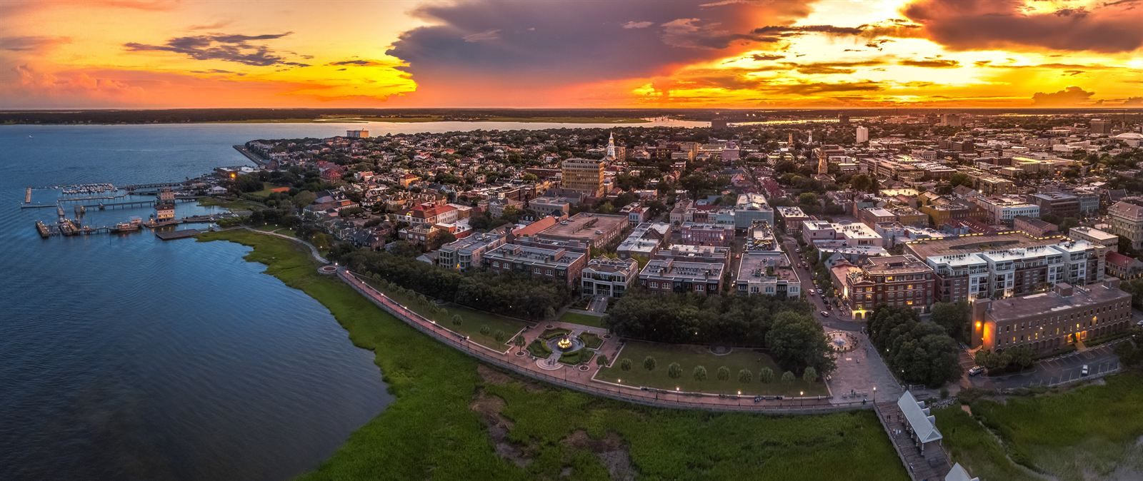 Aerial view of the Charleston peninsula and waterfront park at sunset, with church steeples among the rooftops