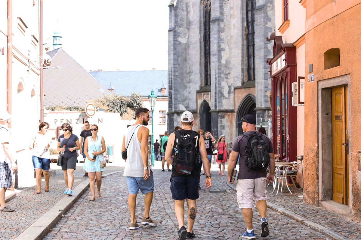 Visitors walking along a sunny cobbled street in a historic European town
