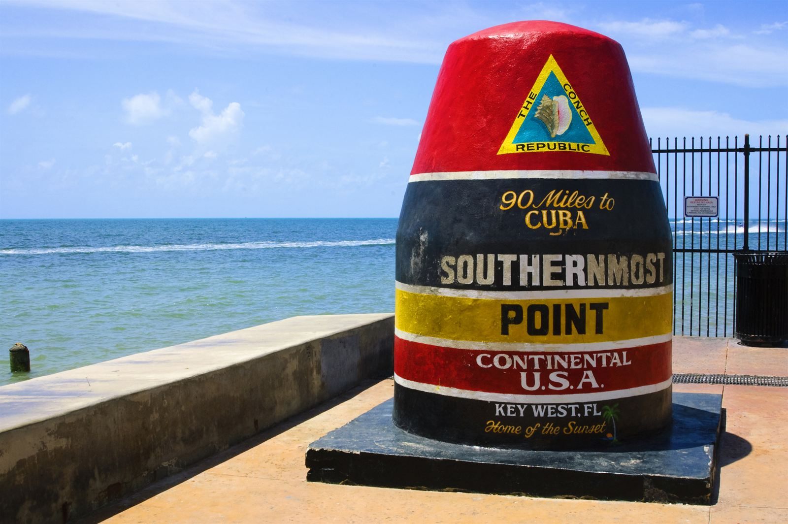 The red, black and yellow Southernmost Point buoy beside the sea in Key West
