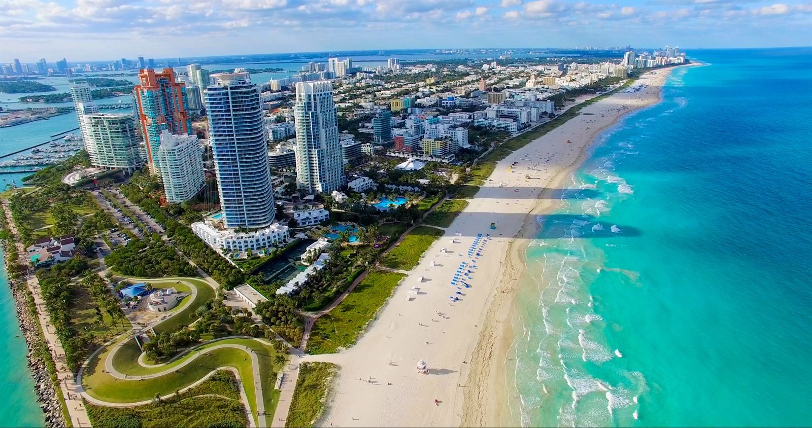 Aerial view of South Beach, Miami, with high-rise towers beside a long sandy beach and turquoise water