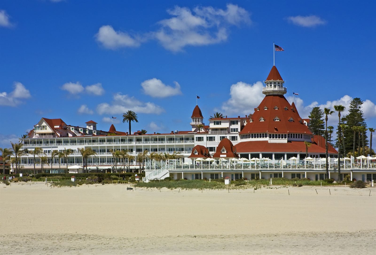 The red-roofed Hotel del Coronado behind a wide sandy beach in San Diego