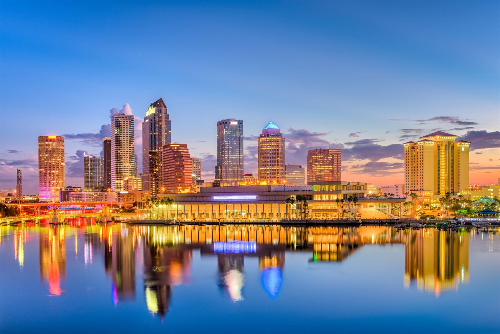 Downtown Tampa skyline lit at dusk and reflected in the calm water of the river
