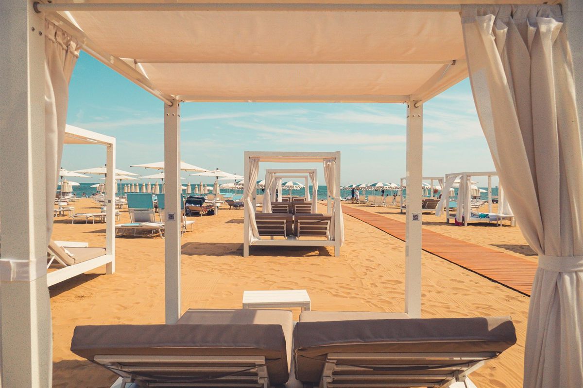 White curtained cabanas with loungers on a sandy beach club